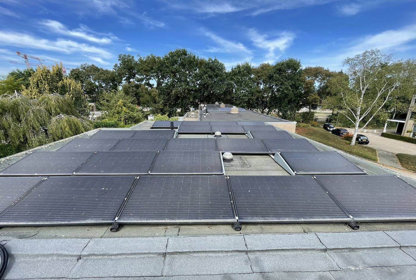 Plat dak met zonnepanelen en de buitenunit van een airco